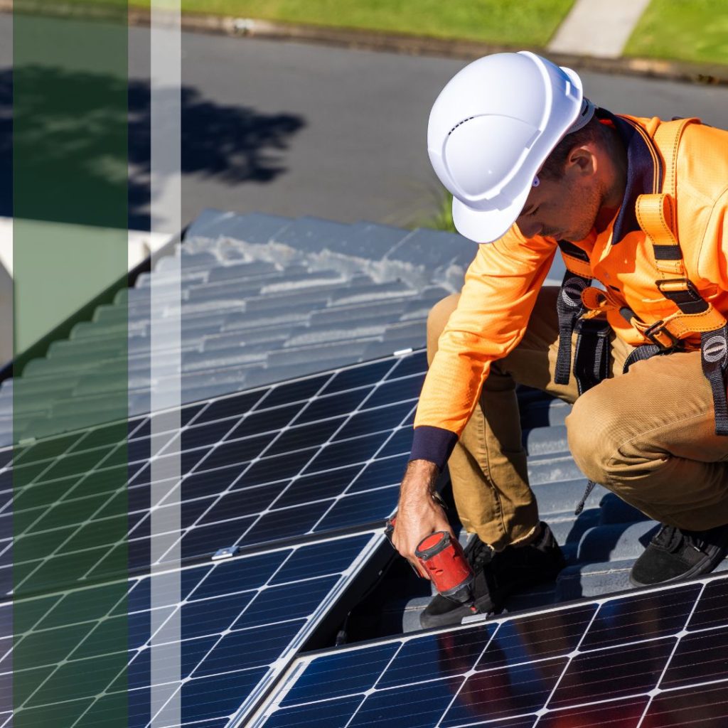 A worker in safety clothes using a drill on a solar panel