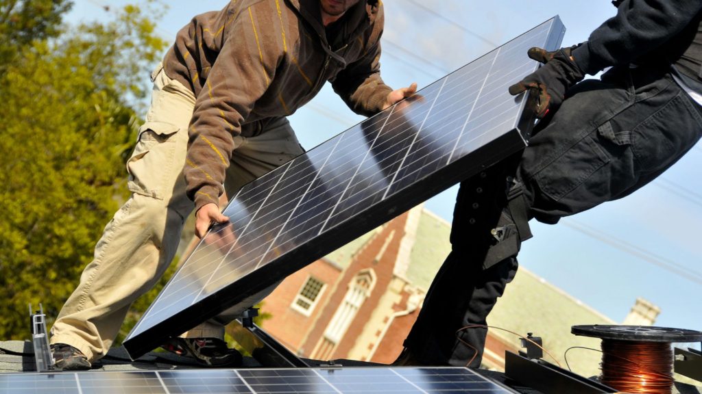 Solar contractors holding a solar panel